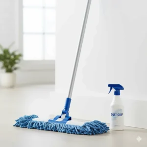 A simple, clean product shot of a dust mop leaning against a wall with a bottle of dust mop spray placed neatly beside it.