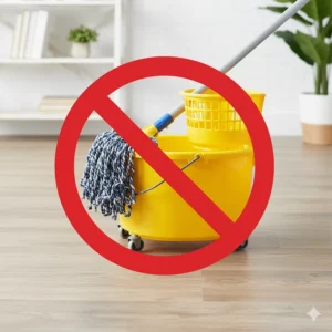 A spin mop and bucket, with a red "X" over the bucket, to advise against using a traditional spin mop with excessive water on LVP.