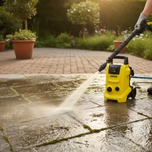 Miniature high-pressure washer removing moss and grime from a concrete patio or stone walkway, showcasing its effective surface cleaning.
