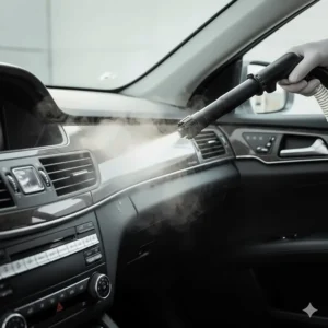 Close-up of the automotive steam vacuum cleaner nozzle releasing hot steam to sanitize a car's dashboard and vents.