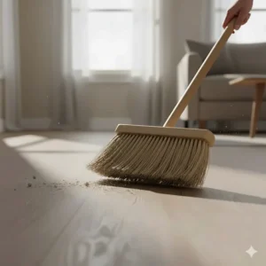 An illustration showing the proper technique for sweeping luxury vinyl plank floors with a soft-bristle broom to avoid scratching the surface.