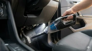 A wet dry handheld vacuum for car interiors with a built-in LED light illuminating dust under the dashboard.