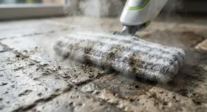Close-up of a microfiber pad on a steam mop for tile and grout lifting grime and debris from textured stone tile.