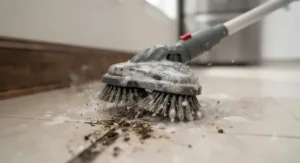 Detailed view of rotating brushes on a tile and grout cleaning machine lifting dirt from deep grout lines.