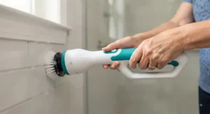 Close-up of an elderly person holding a power scrubber with an easy-grip handle designed for limited hand strength.