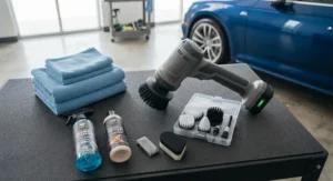 A professional-grade cordless spin scrubber laid out next to microfiber towels and car cleaning products.