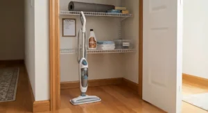 A compact electric steam mop stored neatly in an American home utility closet.