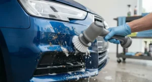 A detailer using a waterproof electric spin scrubber to wash stubborn bugs off a car bumper.