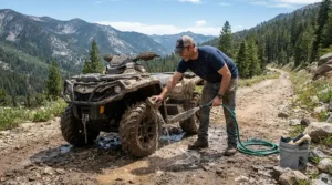 A compact pressure washer with water tank for remote areas washing an adventure vehicle on a dirt trail.